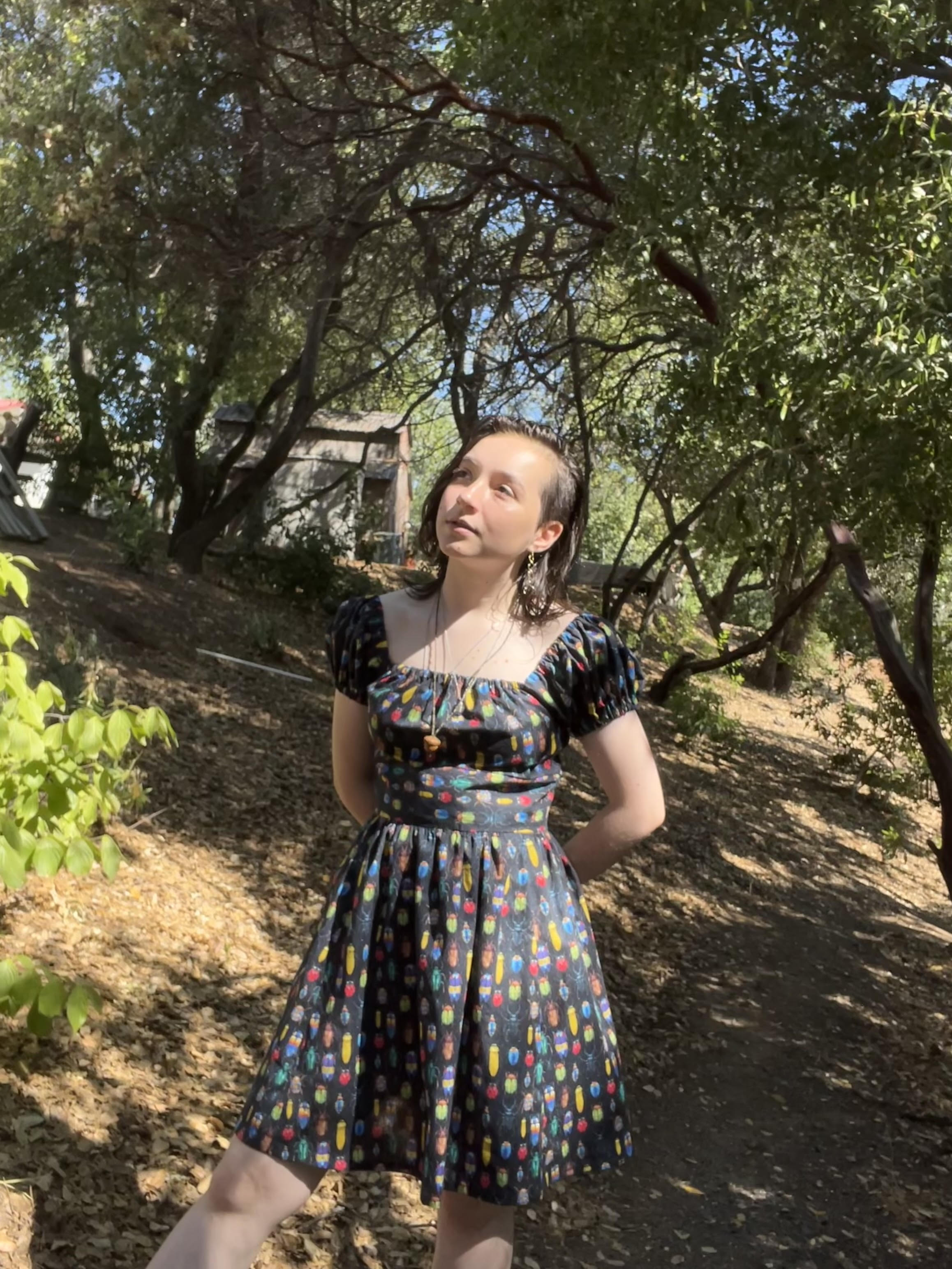 Mia stands in a wooded area in the same dress