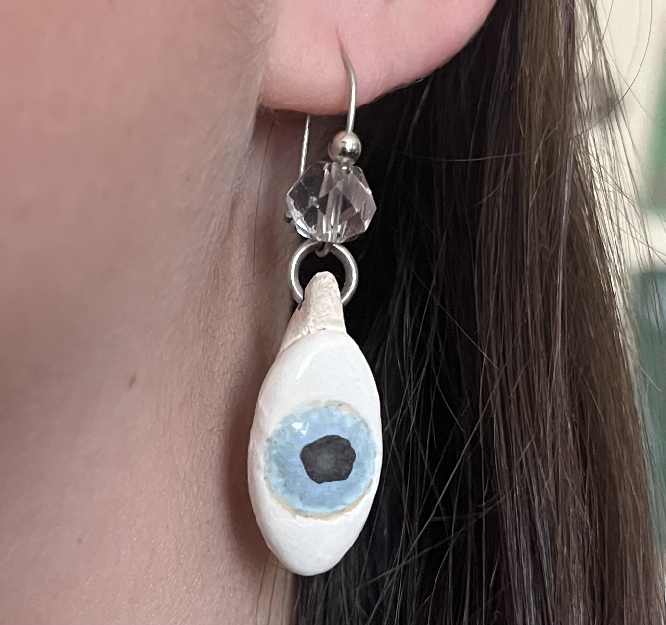 An earring of a sideways eye hangs from an ear