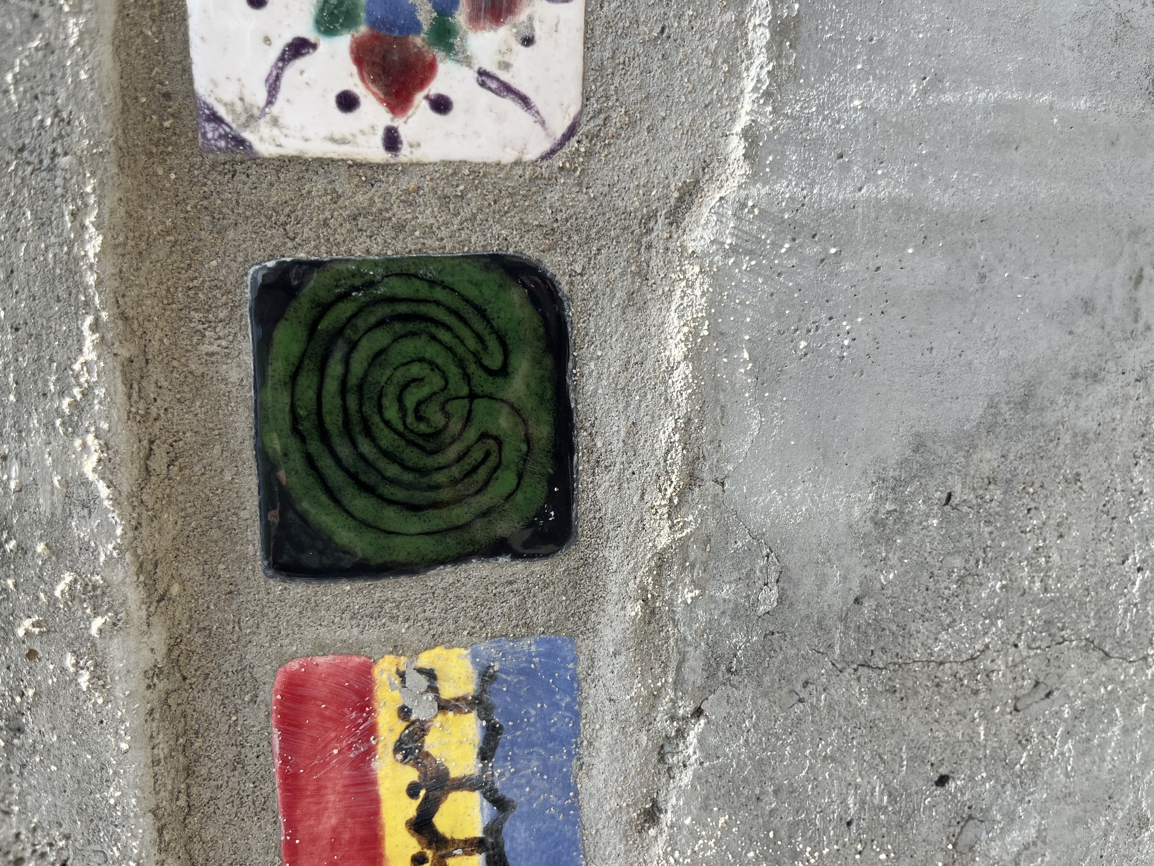 A green moss-like pattern of the labyrinth on a black background of a small tile in a wall