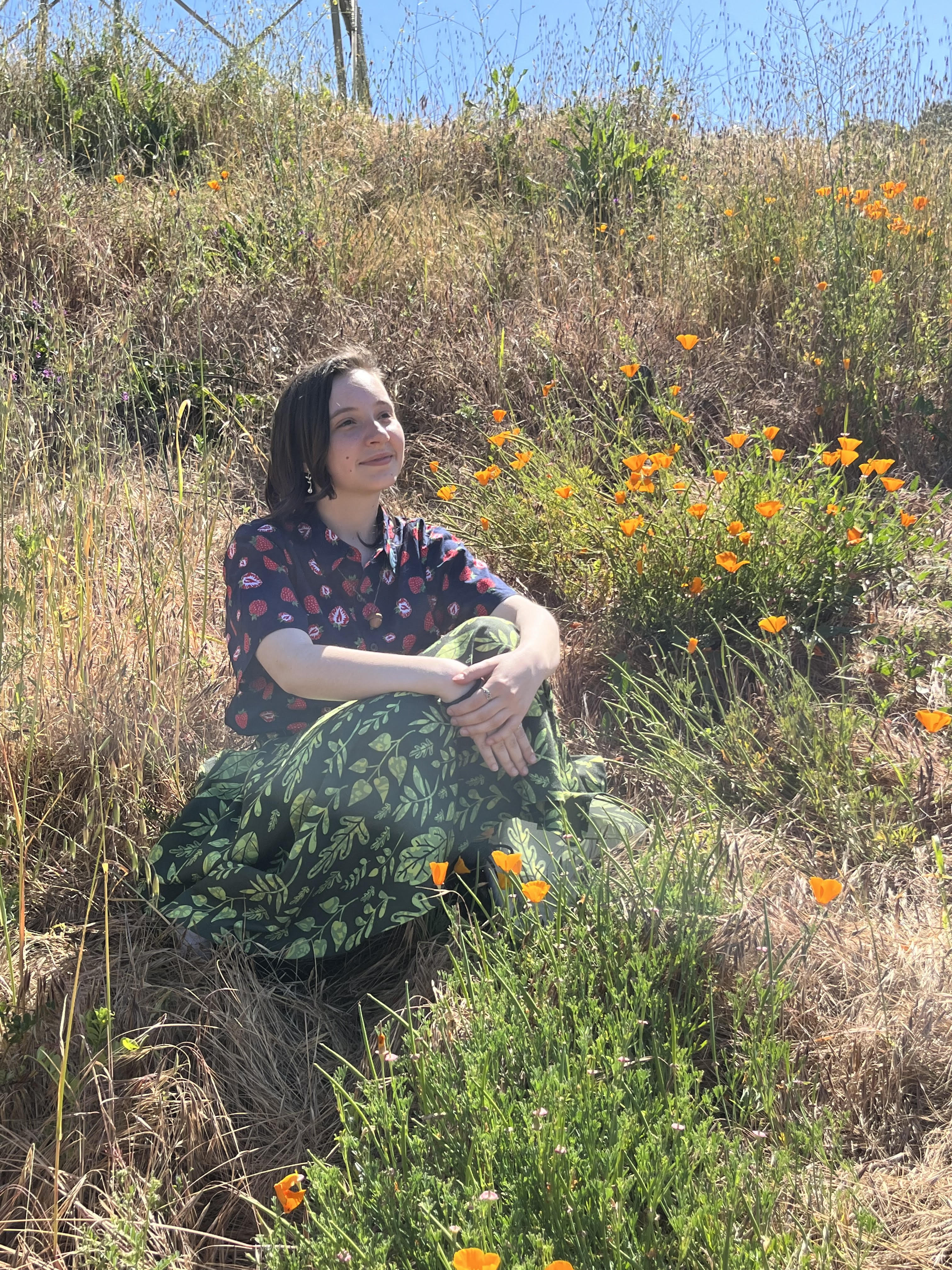 Mia sits on a hill in same outift