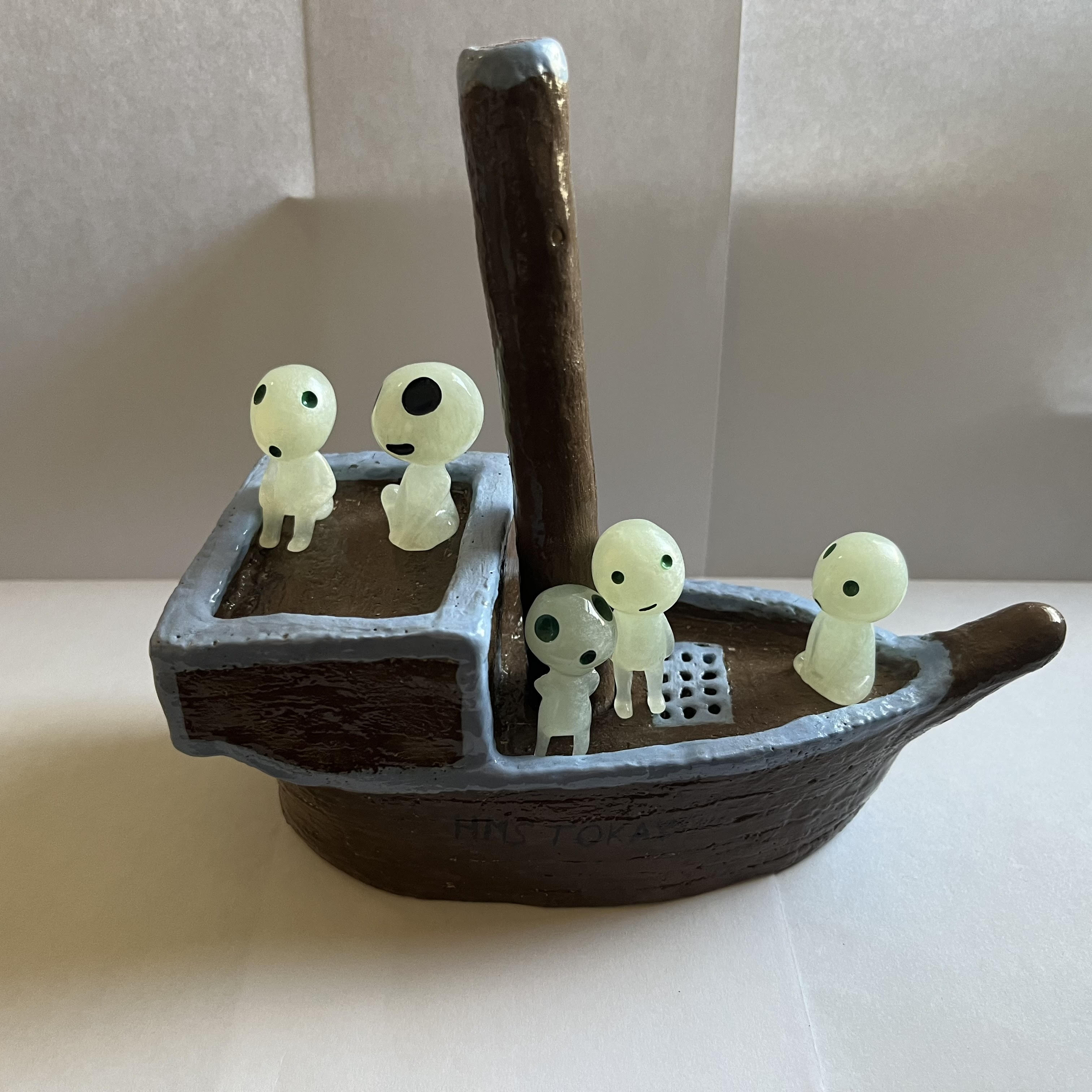 A ceramic wooden patterned sailboat with blue trim and one mast