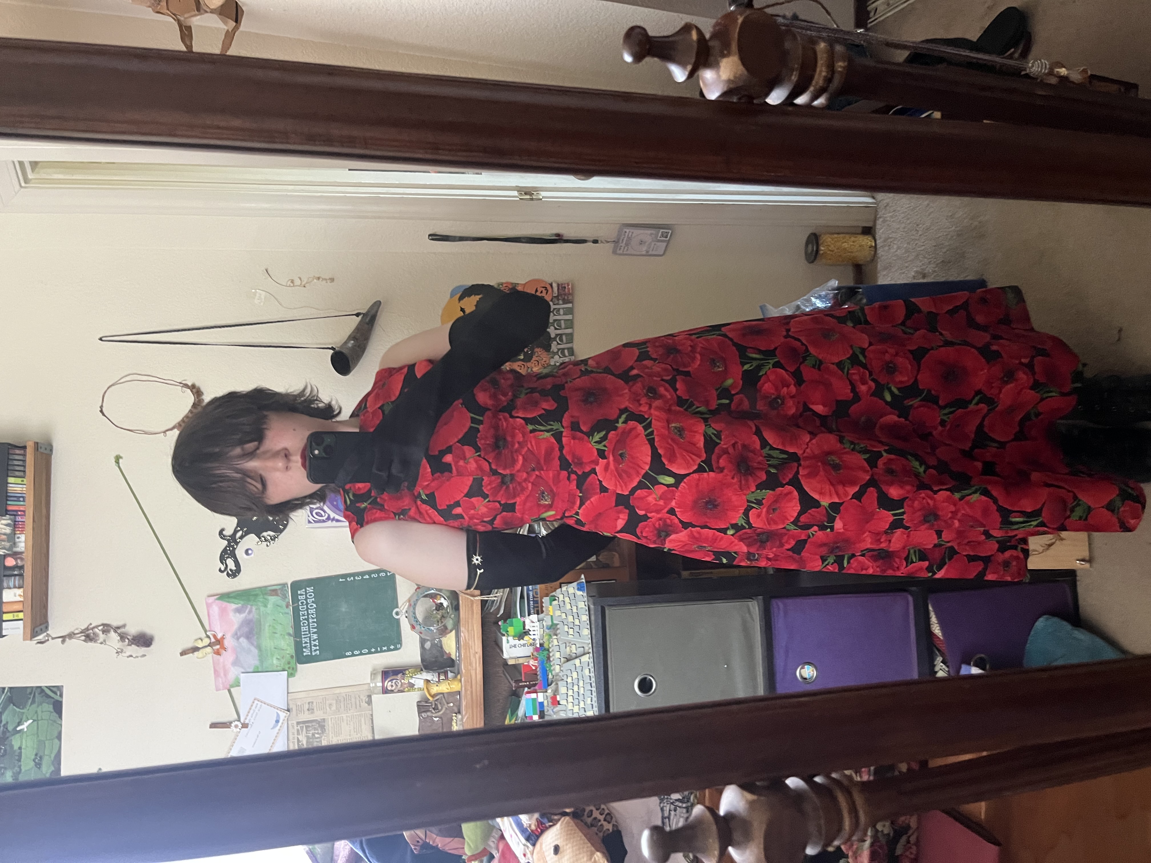 Mirror selfie of Mia in arm length black gloves and a long red poppy patterned dress