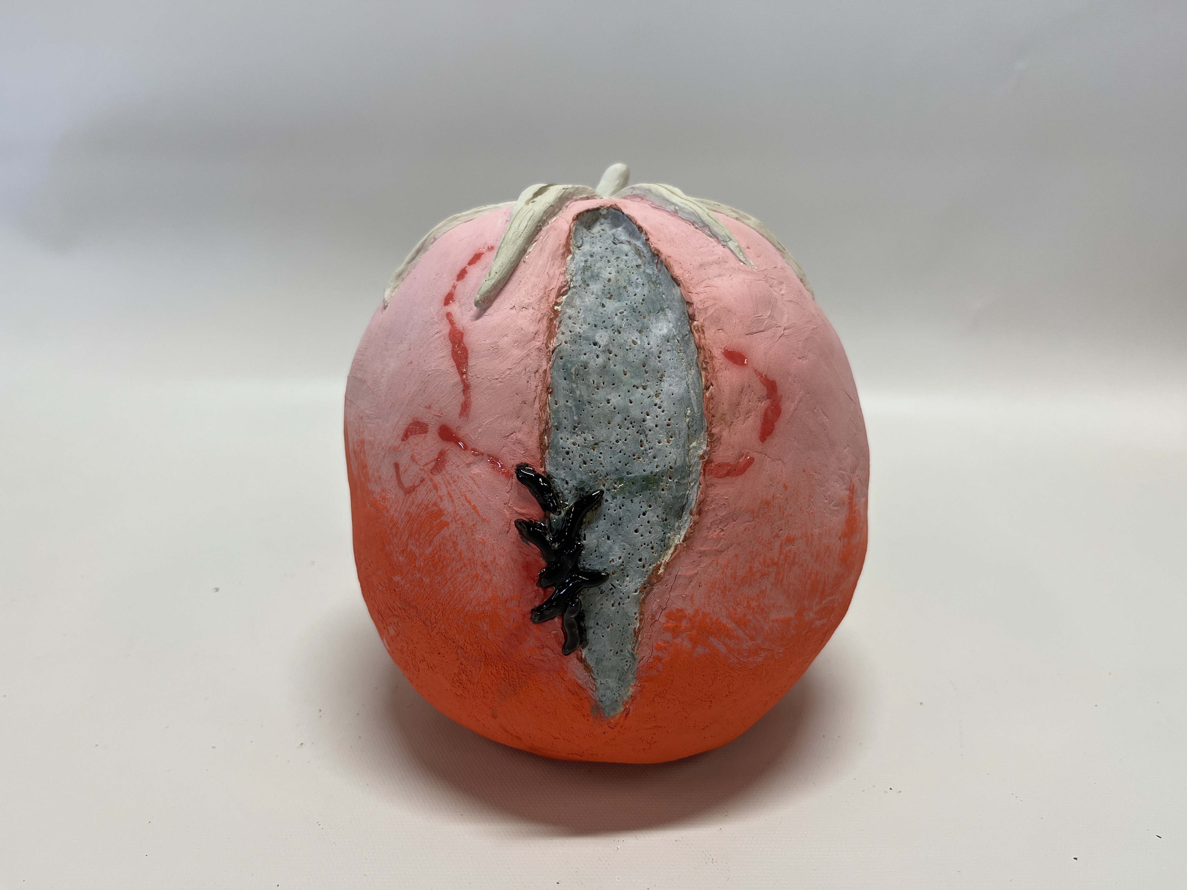 A ceramic tomato with a moldy split down the middle that slugs are crawling out of